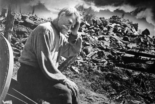 Resident of a village burned down by Germans sitting by the ruins of his house