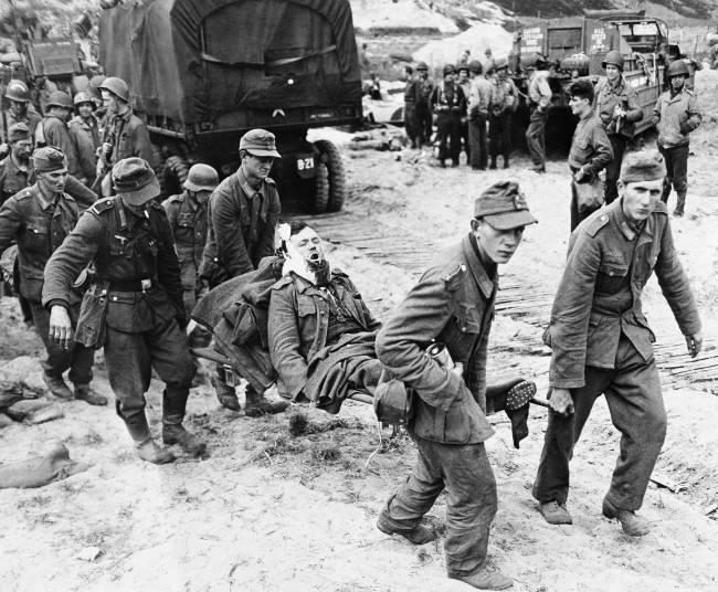 German prisoners, carry comrade to an evacuation area