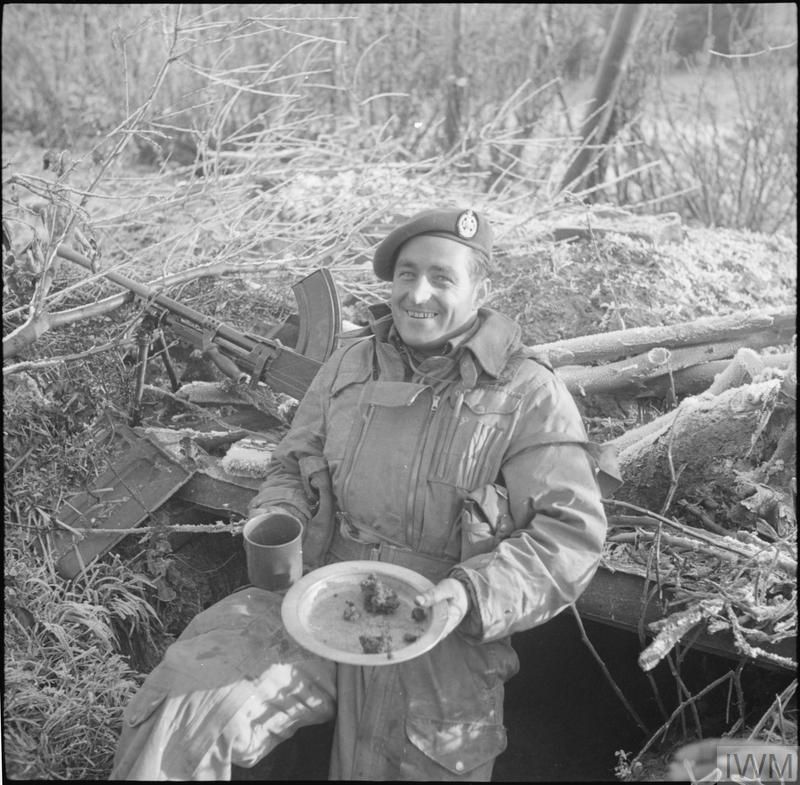 Rifleman Corker of 1st Rifle Brigade enjoys Christmas lunch in his foxhole
